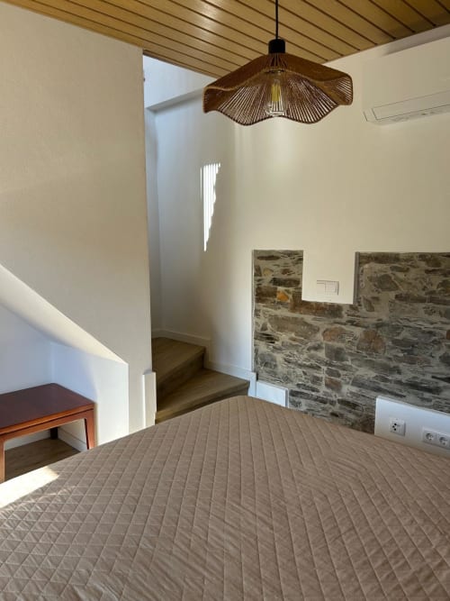 Quarto moderno na casa rural Casas do Sinhel em Alvares, com parede de pedra, luminária pendente e vista para a serra