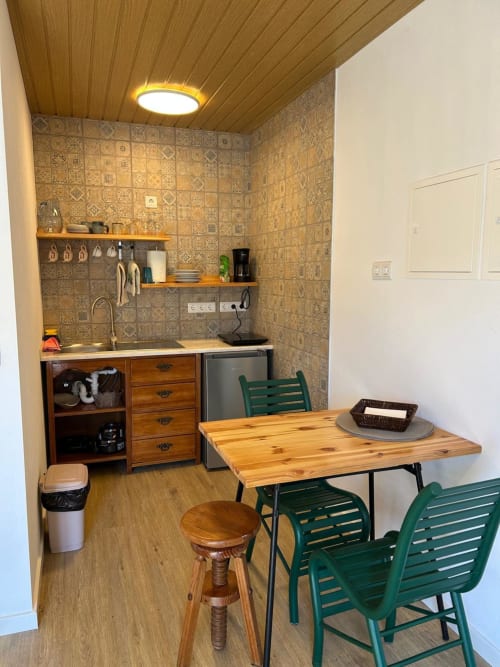 Kitchenette compacta e zona de refeições na cottage Curral em Casas do Sinhel, Alvares, com teto de madeira e azulejo estampado