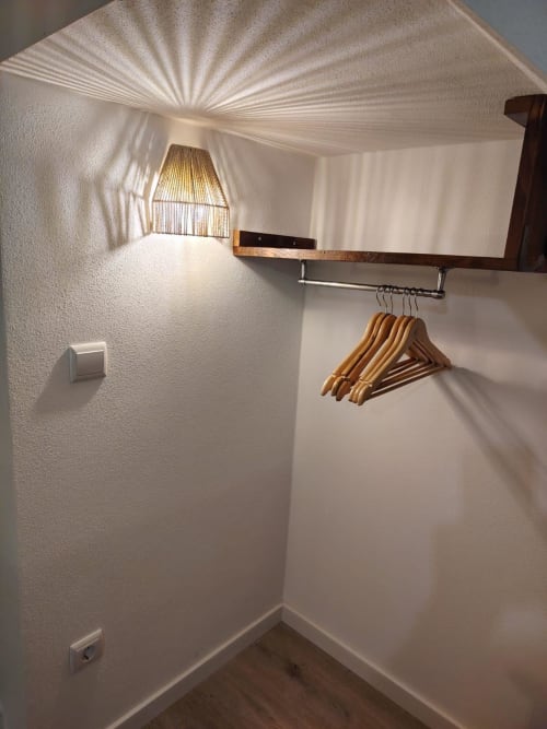 Espaço luminoso do guarda-roupa na casa de hóspedes Casas do Sinhel com cabideiros de madeira, prateleiras na parede e luz natural da janela transom