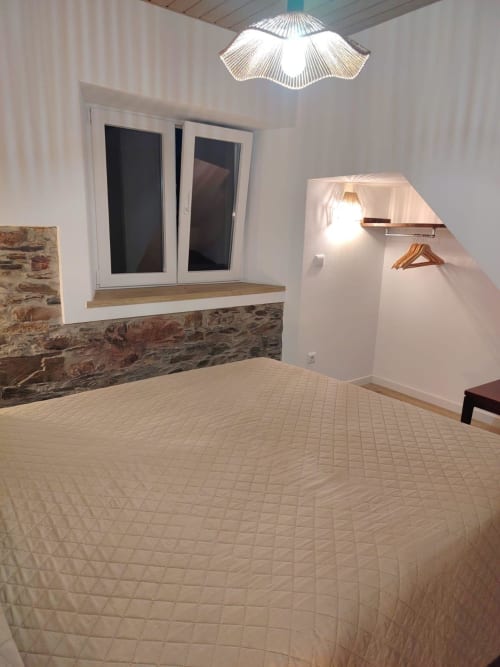 Quarto moderno da Casinha Curral em Casas do Sinhel, Álvares, com parede de pedra, cama acolchoada e luminária de design
