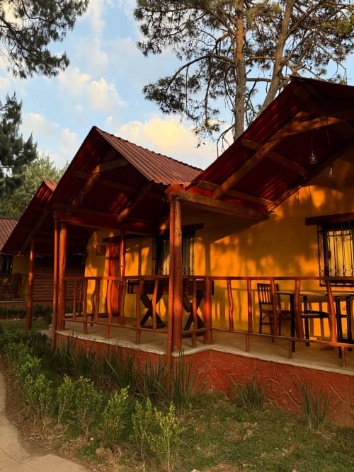 Suite Cabaña Oyamel en Cabañas el Encanto, Las Vigas con villa de tejado rojo, porche de madera y vistas al jardín