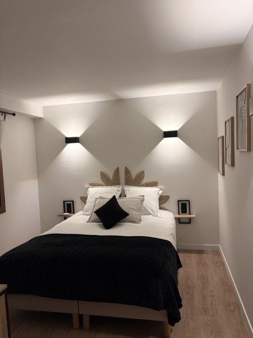 Chambre moderne à l'Hôtel les Vieilles Pierres à Eymet avec lit, luminaires géométriques muraux et vue sur le jardin