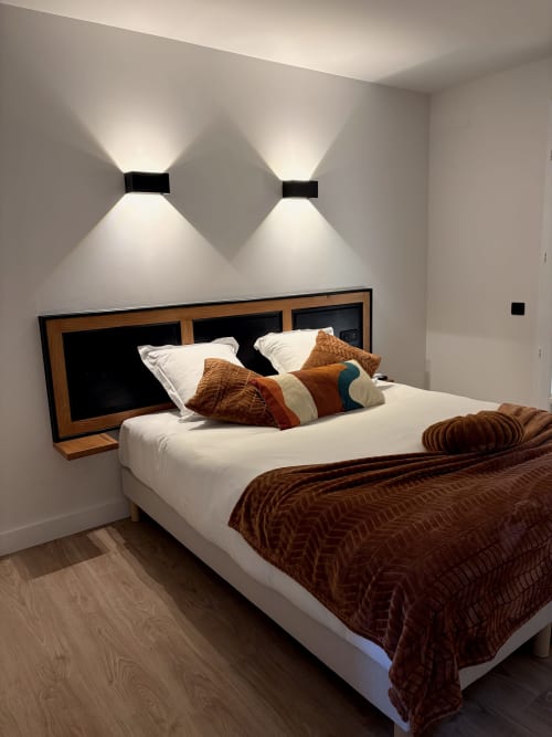 Chambre moderne à l'Hôtel les Vieilles Pierres à Eymet avec lit blanc, literie marron, tête de lit en bois et mur contemporain