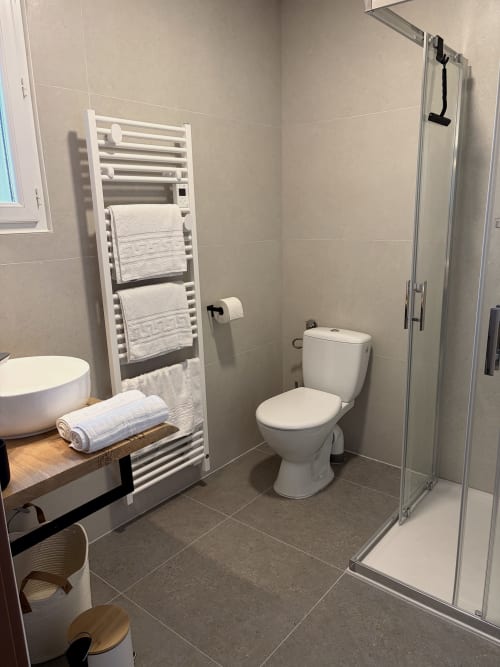 Salle de bain moderne à l'Hôtel les Vieilles Pierres à Eymet avec radiateur sèche-serviettes chauffant, toilettes, lavabo et douche