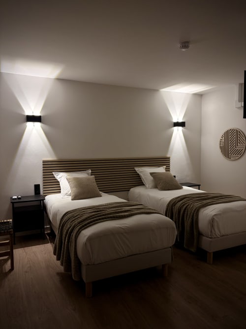 Chambre moderne de l'Hôtel les Vieilles Pierres avec lits jumeaux, appliques murales et décoration épurée à Eymet