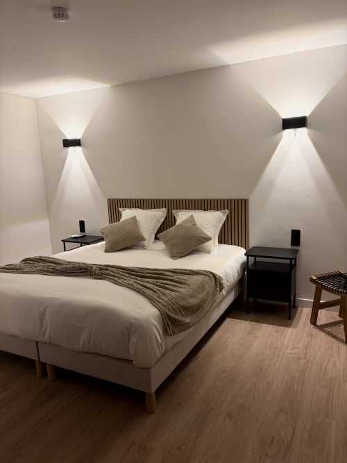 Chambre double moderne à l'Hôtel les Vieilles Pierres à Eymet avec décor épuré, appliques murales contemporaines et style minimaliste