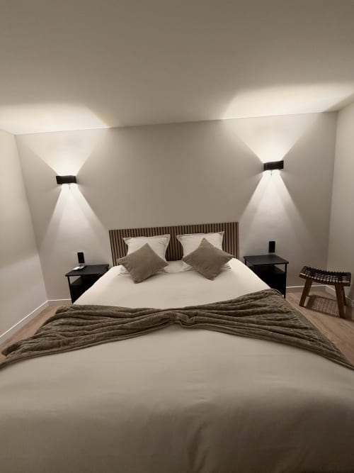 Chambre double moderne à l'Hôtel les Vieilles Pierres à Eymet avec literie blanche, éclairage d'ambiance et tables de nuit sombres