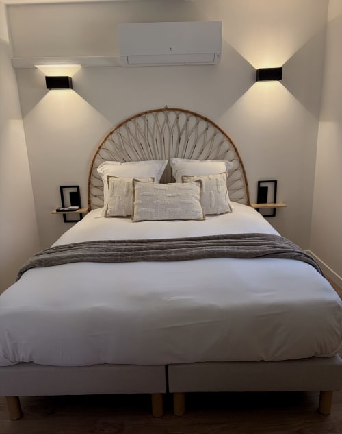 Chambre moderne à l'Hôtel les Vieilles Pierres avec tête de lit tissée, literie blanche, appliques murales et climatisation