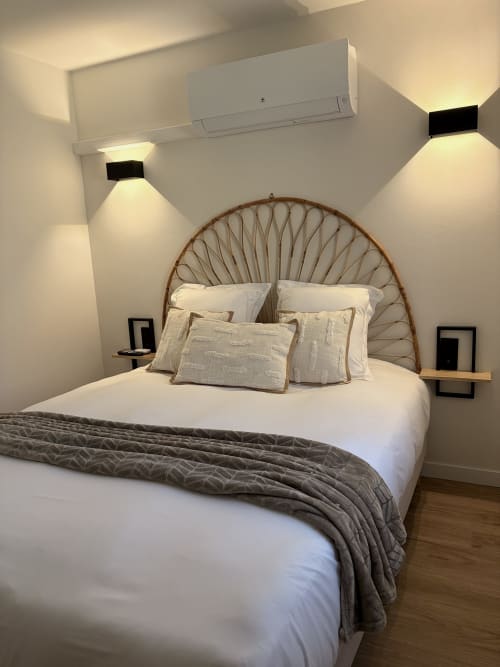 Chambre moderne à l'Hôtel les Vieilles Pierres avec tête de lit tissée, literie blanche, appliques murales et climatisation
