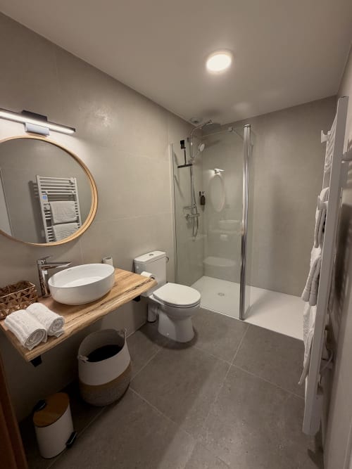 Salle de bain moderne de l'Hôtel les Vieilles Pierres avec vasque blanche, douche à l'italienne, toilettes et radiateur sèche-serviettes