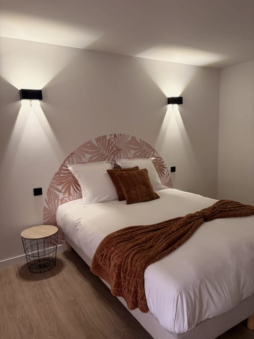 Chambre moderne de l'Hôtel les Vieilles Pierres à Eymet avec lit, tête de lit rose et éclairage indirect