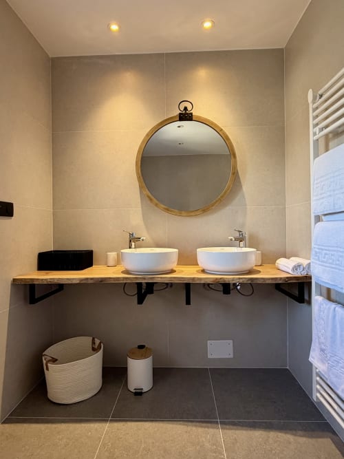 Salle de bain moderne à l'Hôtel les Vieilles Pierres avec deux vasques blanches, miroir en bois et sèche-serviettes électrique