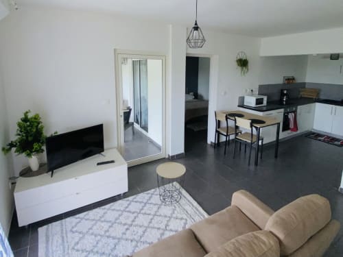 Appartement T3 moderne à Cayenne, séjour ouvert, cuisine aménagée, salle à manger et canapé beige sur carrelage foncé