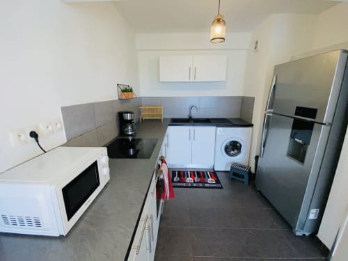 Cuisine moderne du T3 à Maisons En Or, Cayenne avec électroménagers inox, comptoirs noirs et blanc