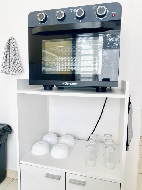 Four à micro-ondes Surfline sur meuble blanc avec accessoires de cuisine dans l'appartement Ibis Rouge aux Maisons En Or, Sinnamary