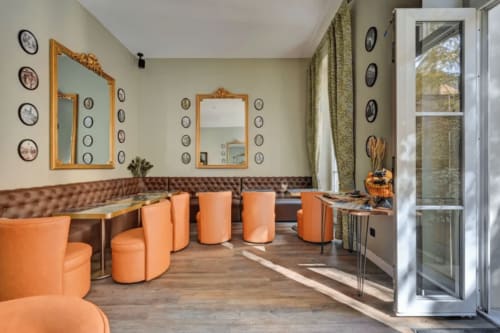 Moderna lounge del Boutique Hôtel Provencia a Marsiglia con sedute cilindriche arancioni, banquette capitonné marrone e cornice dorata