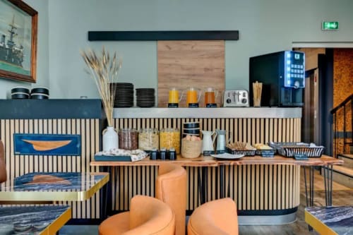 Interno moderno della caffetteria dell'hotel boutique Provencia Marsiglia con pannelli rigati, sedute arancioni e zona bevande