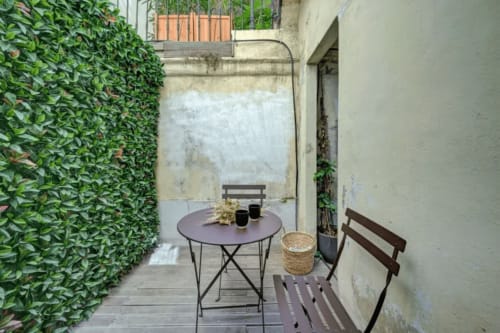 Accogliente patio del Boutique Hôtel Provencia a Marsiglia, con pareti ricoperte di edera, tavolo rotondo e sedie in legno