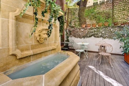 Spa esterna del Boutique Hôtel Provencia a Marsiglia con vasca in pietra, muri ricoperti di edera e ferro battuto