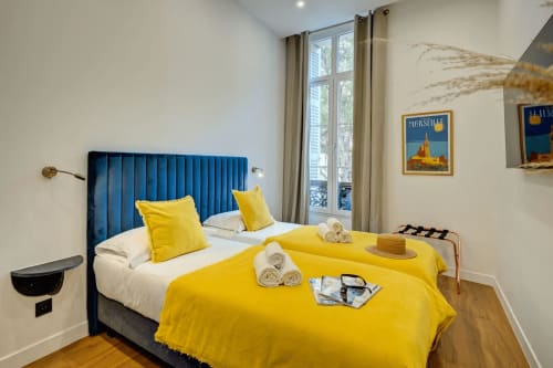 Camera boutique hotel a Marsiglia con testiera in velluto blu, biancheria gialla e servizi moderni