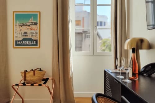 Camera di boutique hotel a Marsiglia con poster turistico, scrivania in legno, bottiglia di vino e vista sul Mar Mediterraneo