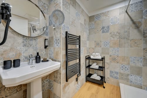 Bagno moderno del Boutique Hôtel Provencia a Marsiglia con piastrelle decorate, lavabo bianco su piedistallo, porta asciugamani nero