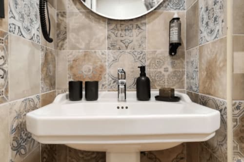 Elegante lavabo da bagno presso il Boutique Hôtel Provencia di Marsiglia, con piastrelle decorative alle pareti e accessori neri