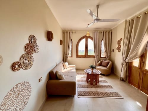 Suite Zahra élégante avec canapés marron, baies vitrées cintrées, décoration bois et vue sur jardin à Dar Lina Guest House