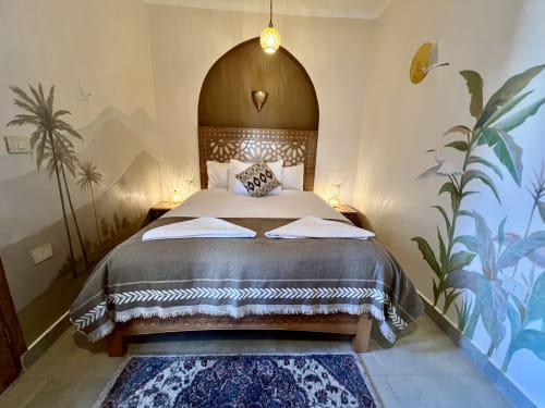 Chambre d'hôtel Luxor avec tête de lit arquée, éclairage ambiant et décoration végétale tropicale