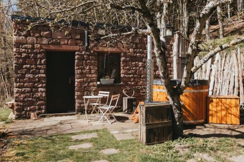 Cabane en pierre rustique aux Cabanes du Nideck à Oberhaslach avec chaises, portails en bois et bouleaux