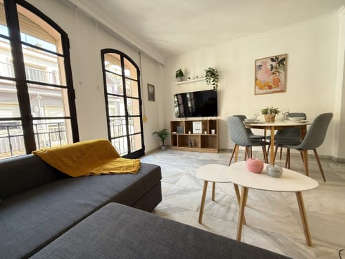 Moderno apartamento en Fuengirola con sala abierta, comedor, sofá, TV, vistas al balcón y mobiliario contemporáneo