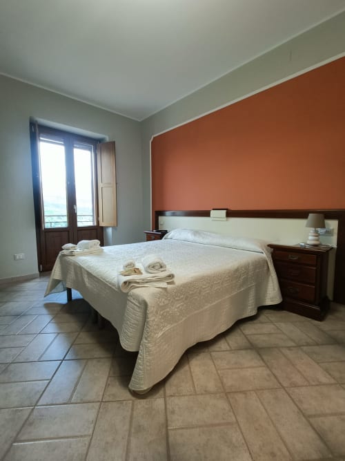 Spaziosa camera da letto all'Affittacamere Il Portale con letto matrimoniale, muro in terracotta e balcone con vista sui monumenti