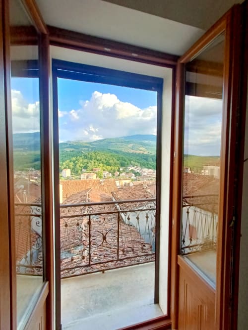 Vista dal balcone della Camera Quadrupla presso Il Portale a Spinoso, con tetti in terracotta, valle e montagne sotto cielo blu
