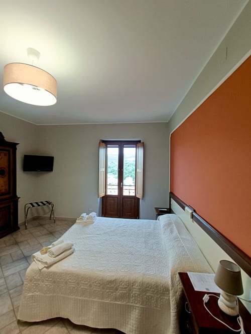 Camera luminosa a Il Portale a Spinoso con letto matrimoniale, balcone con vista sulla campagna e parete accent arancione