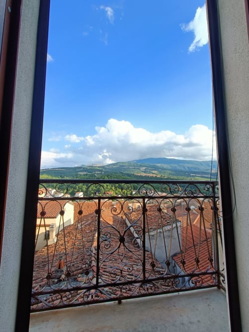 Balcone ornato con ringhiera in ferro che si affaccia su verdi colline e valli vicino a Spinoso, Italia, vista dalla camera d'albergo