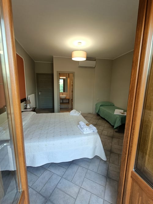 Ampia camera quadrupla presso Affittacamere Il Portale a Spinoso con due letti, bagno privato e accesso al balcone