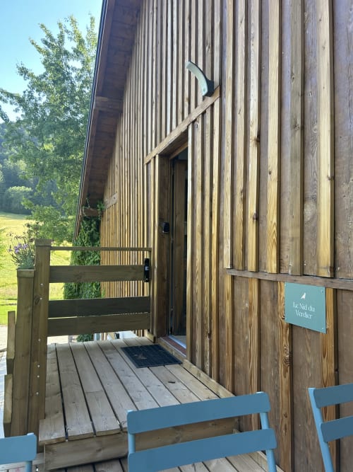 Entrée de cabane en bois aux Cabanes du Nideck, retraite perchée à Oberhaslach avec terrasse et accents bleus