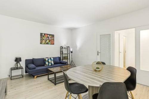 Appartement moderne à la Résidence Aurmat avec table à manger, canapé bleu marine et kitchenette en open-plan