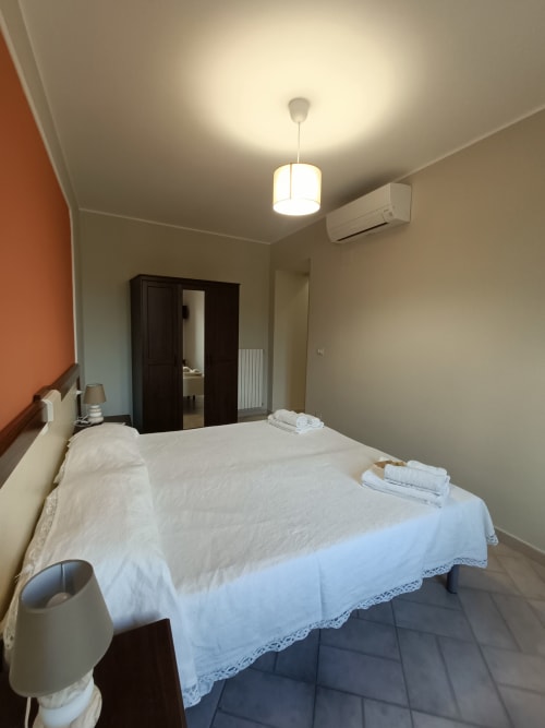 Camera luminosa all'hotel Il Portale a Spinoso con letto matrimoniale, armadio scuro, aria condizionata e lampade a sospensione