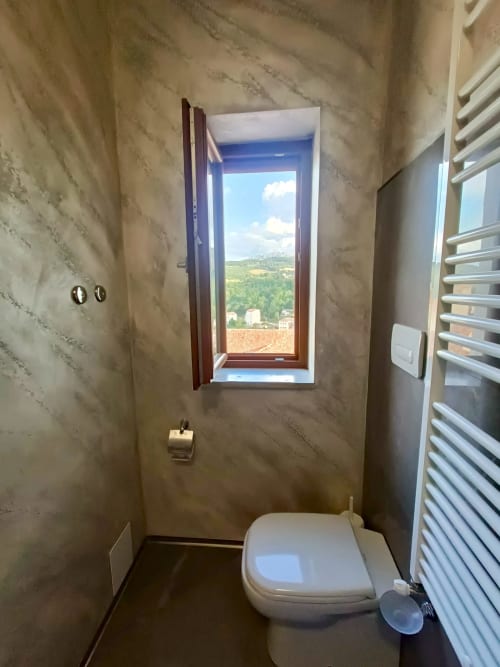 Bagno moderno con finestra panoramica sulle verdi colline toscane dell'hotel Il Portale a Spinoso, Italia