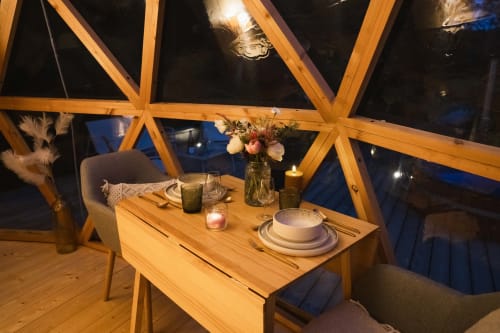 Dîner intime aux Cabanes du Nideck avec table en bois, couverts, fleurs et forêt nocturne