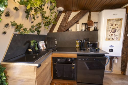 Cuisine compacte de l'appartement L'école des sorciers à Accolade Châteaudun avec électroménagers noirs et herbes suspendues