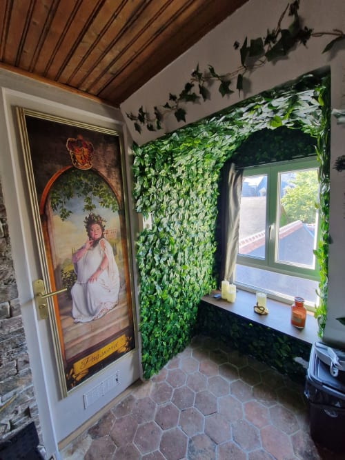 Chambre à thème magique à l'hôtel Accolade à Châteaudun avec murs de lierre luxuriant, tableaux portraitistes et baies vitrées vue sur la ville