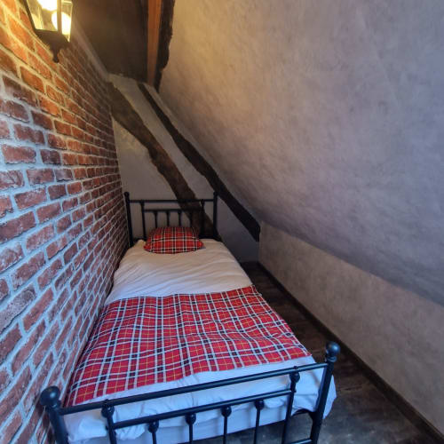 Chambre douillette à L'école des sorciers de l'hôtel Accolade, Châteaudun, avec literie écossaise rouge et murs en briques