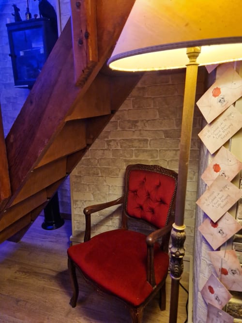 Fauteuil en velours rouge sous une lampe dans l'appartement enchanté d'Accolade à Châteaudun, lettres sur mur de briques