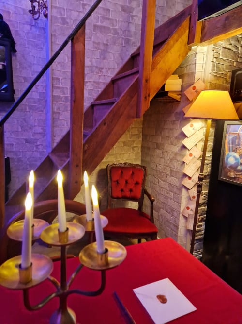 La chambre L'école des sorciers à l'Accolade Châteaudun avec table rouge aux chandelles, escalier en bois et ambiance magique
