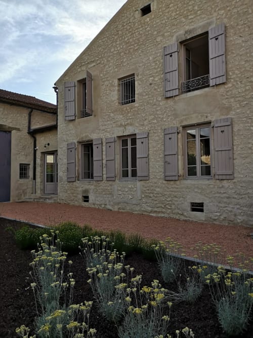 Les Charmises cottage in Charroux with stone facade, purple shutters, and garden courtyard with flowering plants