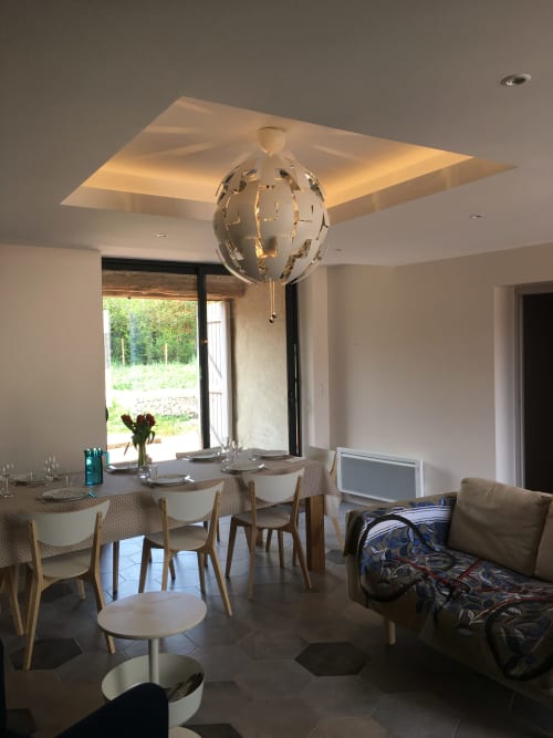 Modern dining area at Les Charmises cottage with spherical pendant light, garden views, and contemporary furnishings