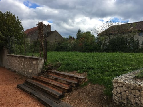 Les Charmises cottage garden view in Charroux with rustic wooden steps, stone walls, and green meadow