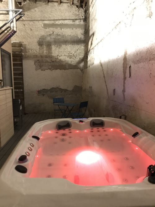 Illuminated red-lit jacuzzi in rustic stone courtyard at Les Charmises cottage, Charroux